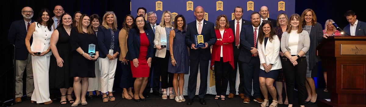This images shows a group of Comptroller employees. The Comptroller is holding a Top Workplaces award plaque.