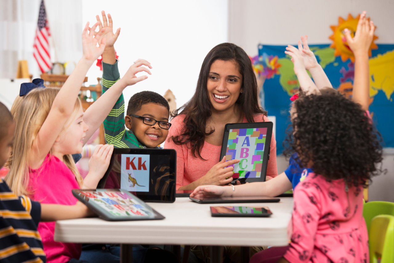 Kindergarten students and teacher using digital tablets