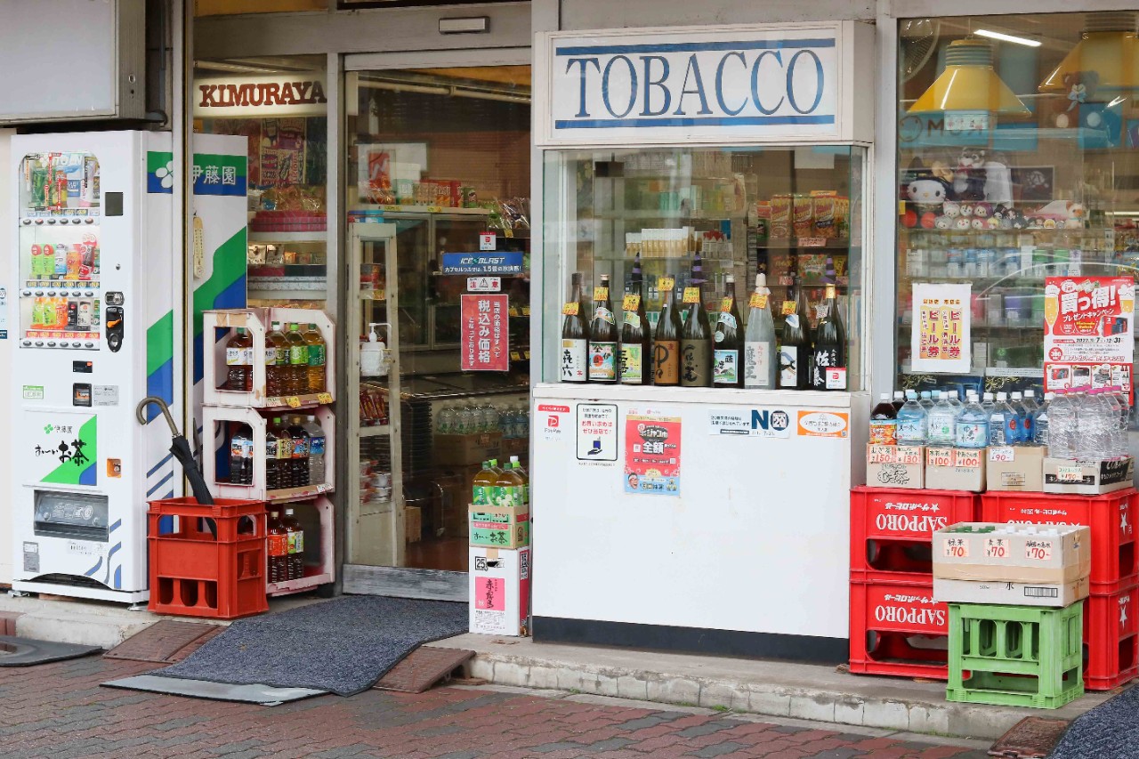 TOKYO, JAPAN - December 22, 2022: A store with alcohol and tobacco displated in its window and a drinks vending machine outside in Tokyo's Tokushima Ward.