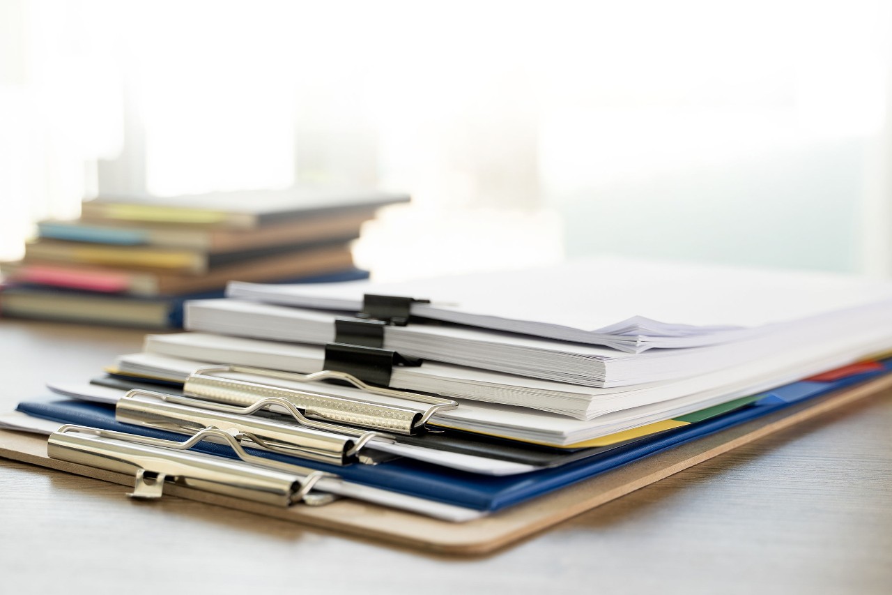stack of clipboards and books on white background