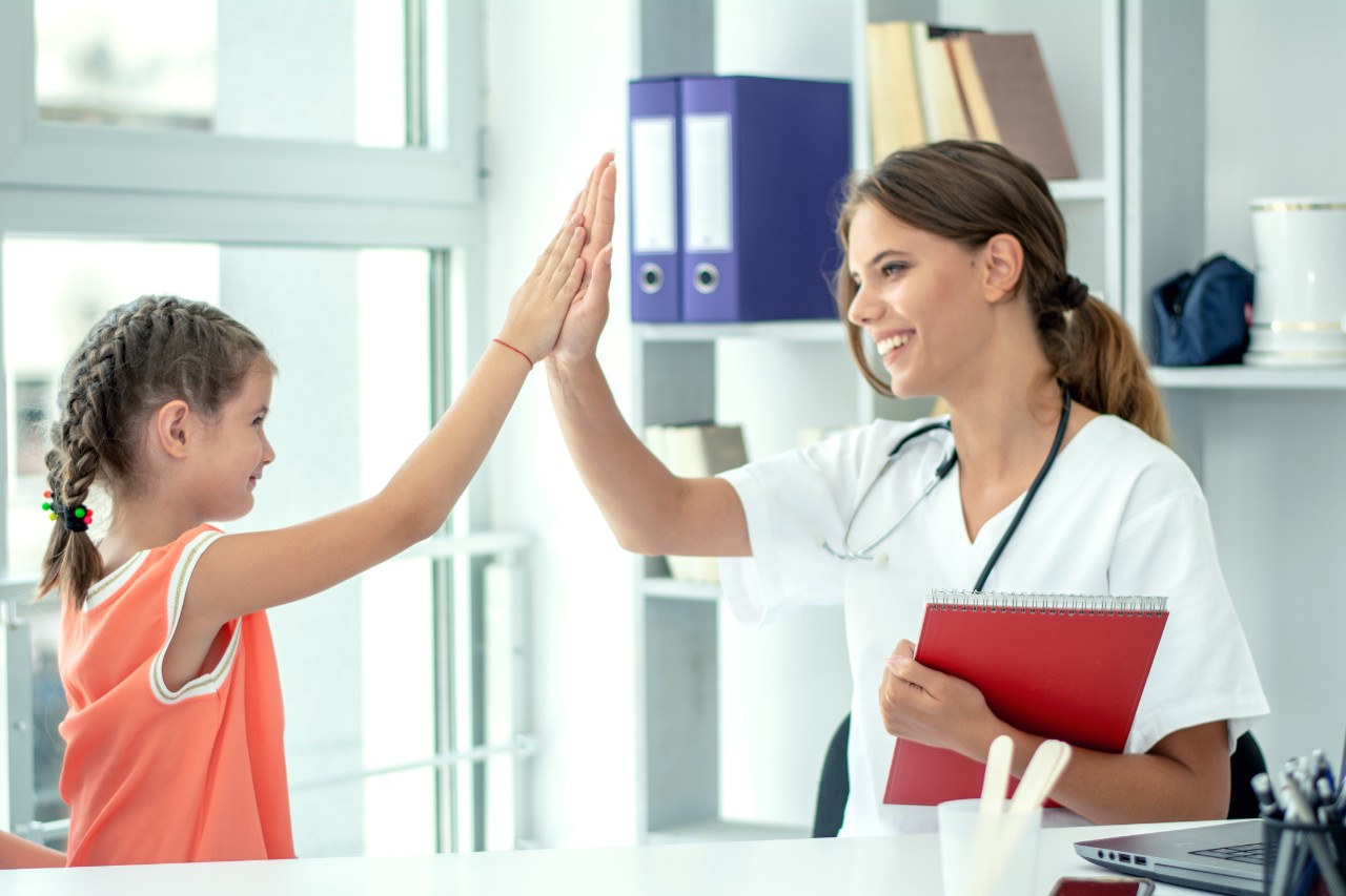 Cute girl and paediatrician doing high five