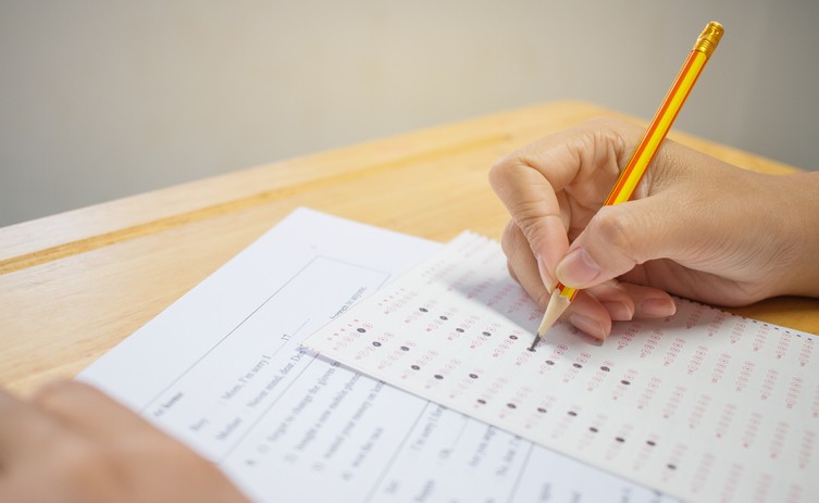 Students hands taking exams, writing examination room with holding pencil on optical form of standardized test with answers and english paper sheet on row desk chair doing final exam in classroom.