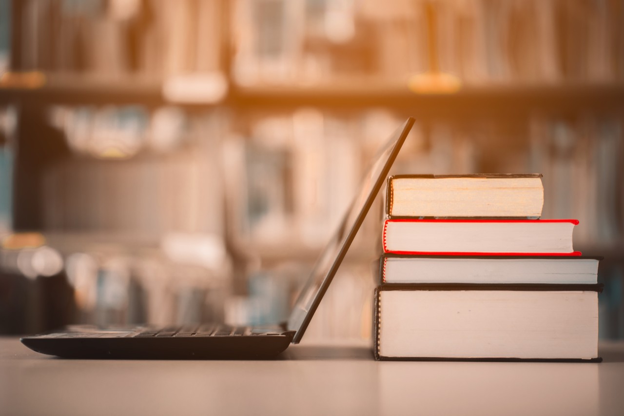 Bookshelves and laptops are placed on the library desk.E-learning class and e-book digital technology