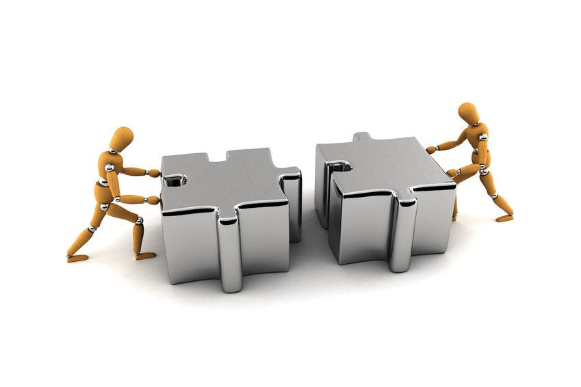 Two wooden mannequins pushing puzzle pieces together