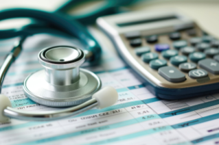 calculator and stethoscope on top of paperwork